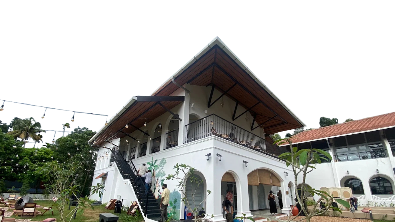 One Kochi's heritage building exterior with a sweeping wooden roof, string lights and staircase