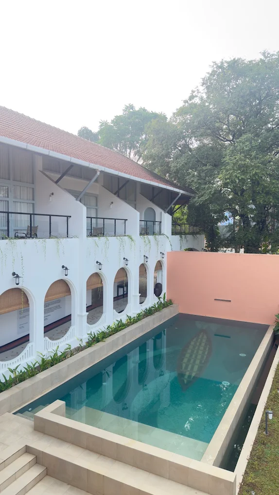 A garden pool at One Kochi framed by white arches and a terracotta roof